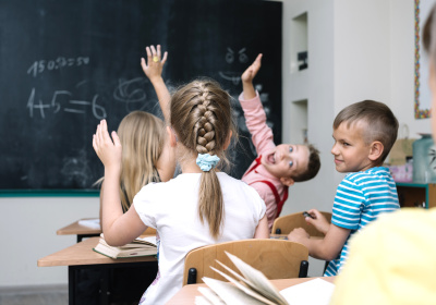 schoolchildren-sitting-classroom-raising-hands