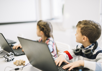 school-children-sitting-with-laptop-looking-blackboard